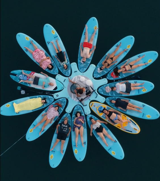 Vista aérea de grupo sobre tablas de paddle surf en círculo durante baño de sonido en Valencia