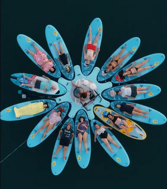 Vista aérea de grupo sobre tablas de paddle surf en círculo durante baño de sonido en Valencia